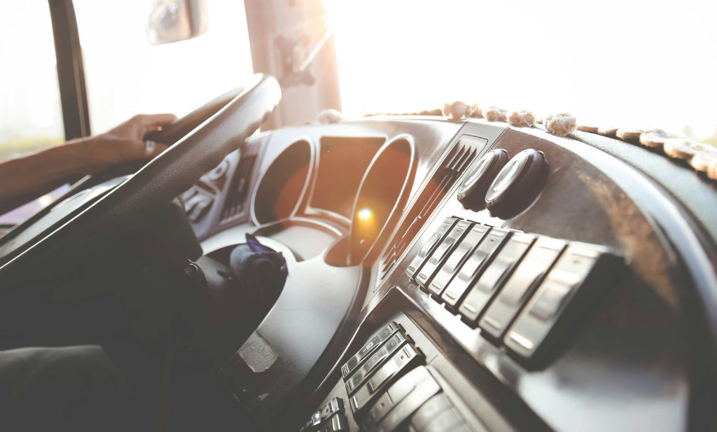 mão do motorista está sob o volante, aparece o painel do caminhão